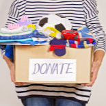 A person holding a box of clothes labeled "Donate"