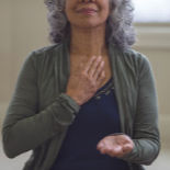 Gray-haired woman breathing with her hand on her heart.