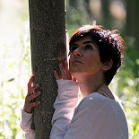Woman hugging a tree, looking up.