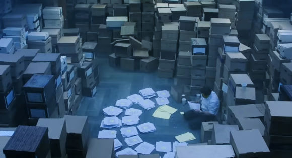 Mark Ruffalo as Robert Billott looking at piles of paper with information.