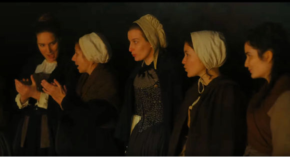 Five women in white caps singing in Portrait of a Woman on Fire