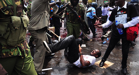 Boniface Mwangi being assaulted by the police during a demonstration.