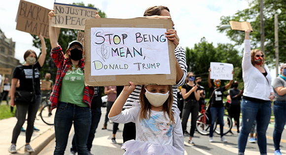 A young girl holds up a sign asking Donald Trump to stop being mean.