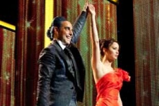 Stanley Tucci as Caesar and Jennifer Lawrence as Katniss