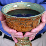 Closeup of a man's hands holding a homemade ceramic challis.